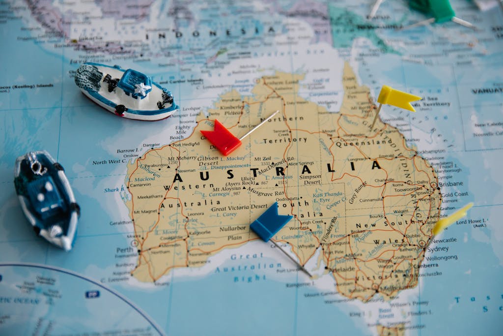 Toy Ships and Flags on Australia Map - best city to invest in australia