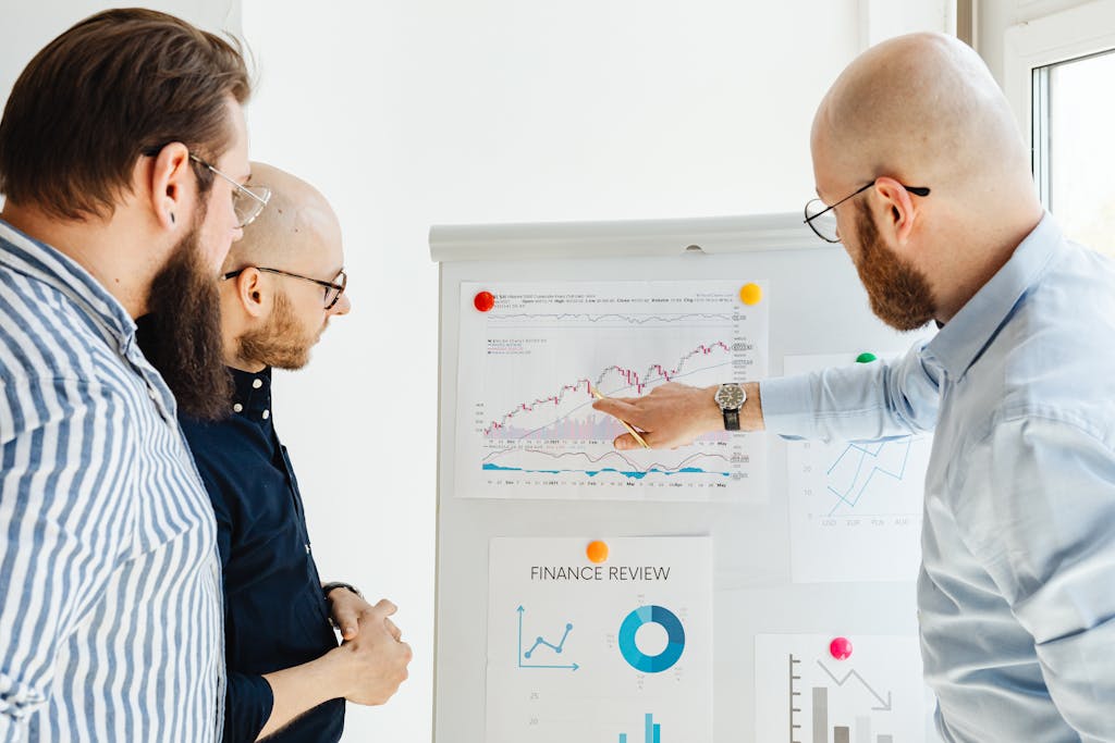 Three Men Discussing a Finance Report - areas to invest in property